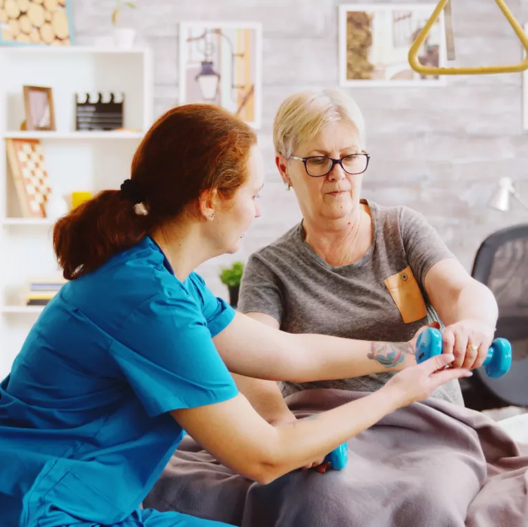 revealing shot female nurse helping elderly woman recover her muscles after accident she is lying hospital bed retirement home scaled e1719241483499