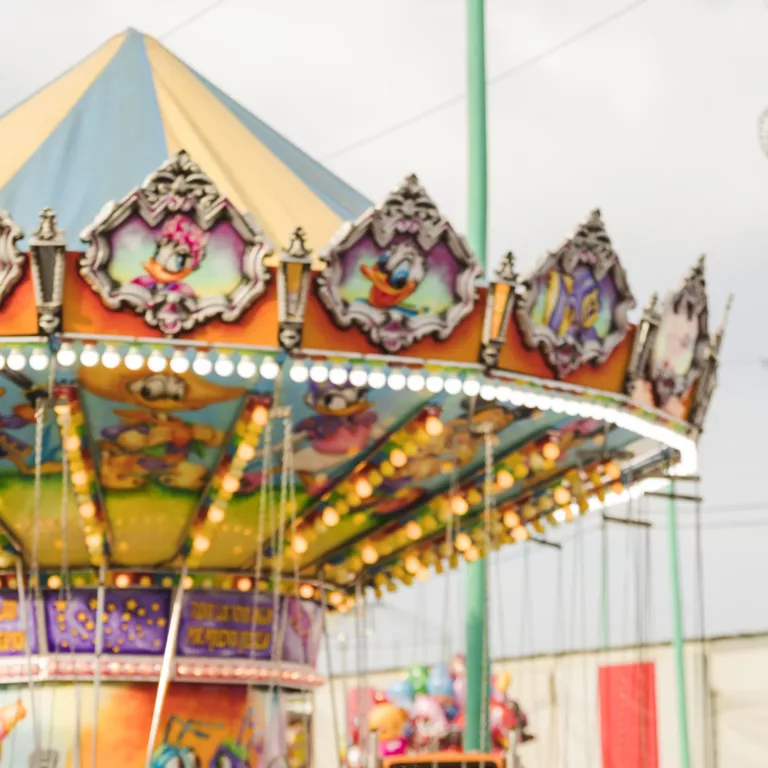 two smiling young woman embracing front illuminated colorful carousel scaled e1719393474558